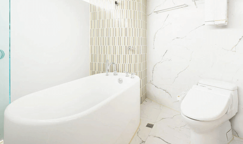 【大安住宿】柯達大飯店台北敦南浴室 —— 現代化浴室設有獨立浴缸與馬桶，採用白色大理石與淺色瓷磚設計，乾淨明亮。