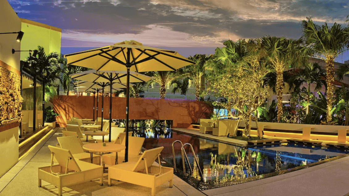 【那霸住宿】棕櫚皇家度假飯店國際通外觀 — 白色多層建築外觀，入口處有飯店招牌與綠植裝飾，位於市區街道旁。