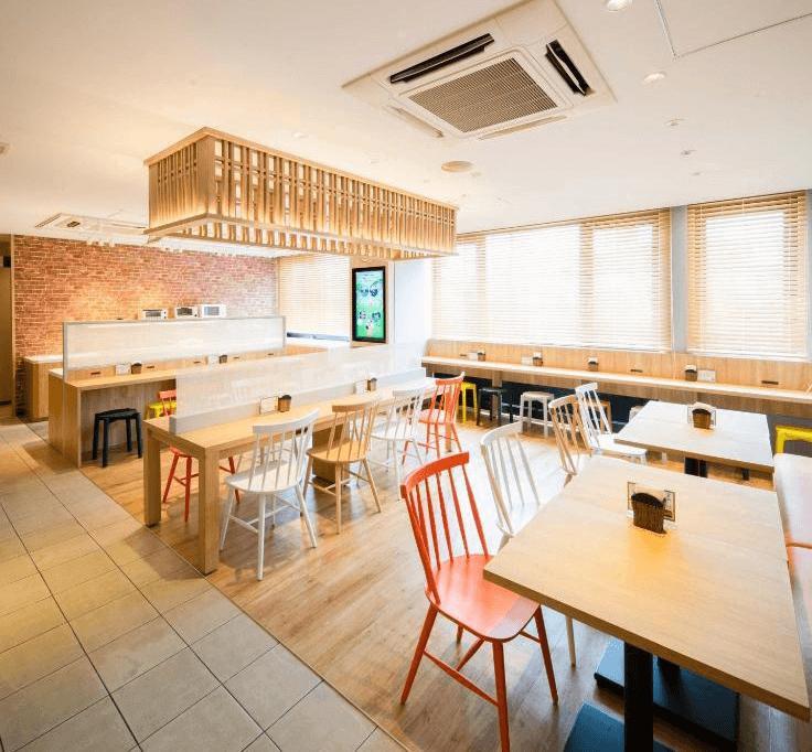 【名護住宿】沖繩名護超級酒店 (Super Hotel OKINAWA NAGO) 用餐區，明亮開放式設計，木質桌椅搭配溫暖燈光，提供早餐與休憩空間。