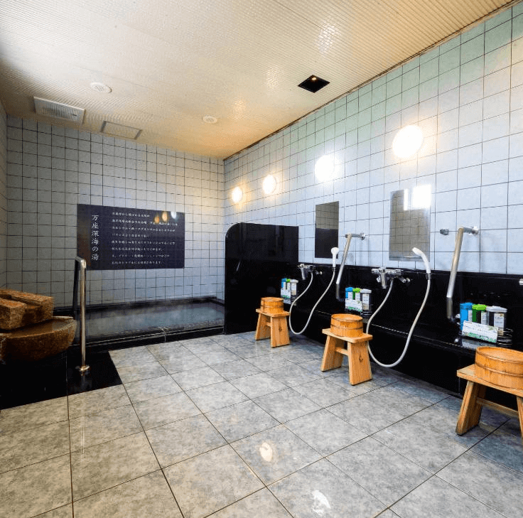 【名護住宿】沖繩名護超級酒店 (Super Hotel OKINAWA NAGO) 大浴場設施，傳統日式洗浴空間配有洗浴座椅、淋浴設備與溫泉浴池，環境整潔舒適。