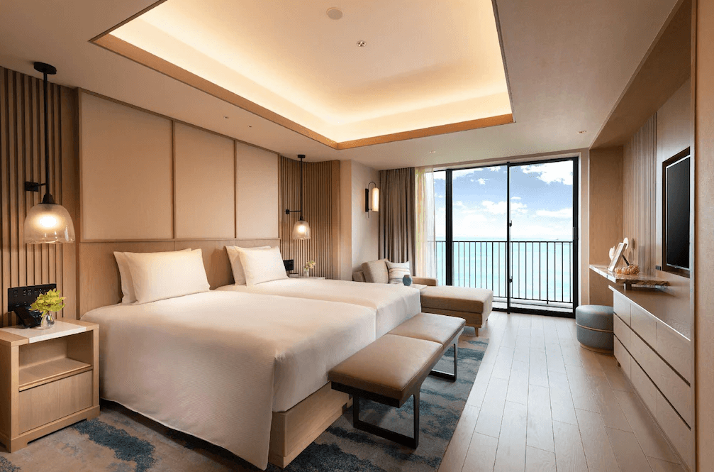 【宮古島住宿】沖繩宮古島希爾頓度假酒店的現代風格海景雙床房，設計簡約優雅，大片落地窗可眺望蔚藍海景，搭配舒適沙發區與寬敞空間，營造放鬆度假氛圍。