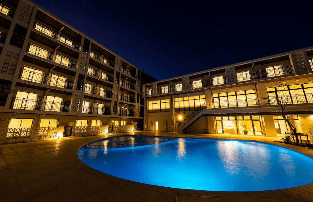 【宮古島住宿】沖繩宮古島托麗芙特度假酒店夜景一隅，圓形泳池在暖黃燈光襯托下別具風情，環繞四層樓住宿空間，展現南國度假飯店的悠閒氛圍。