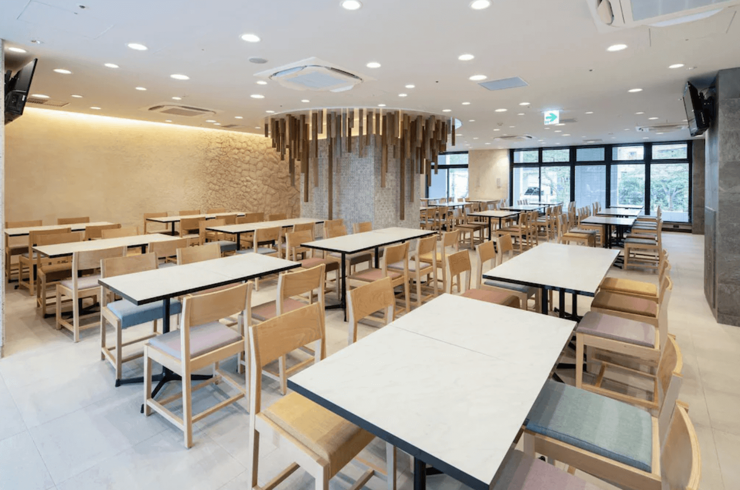 【那霸住宿】沖繩逸之彩飯店餐廳 — 明亮寬敞的用餐空間，木質桌椅整齊排列，天花板懸掛木質裝飾。