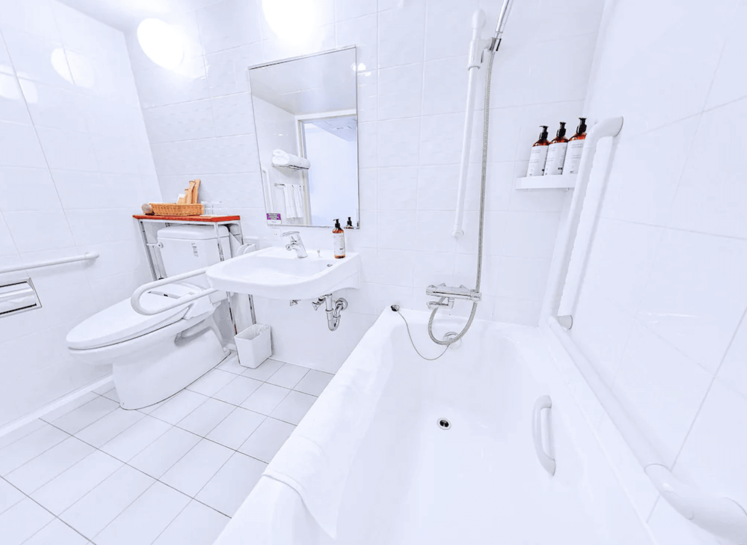 【那霸住宿】沖繩那霸美居飯店浴室 — 全白設計的浴室，設有浴缸、免治馬桶、洗手台與掛牆式沐浴用品。