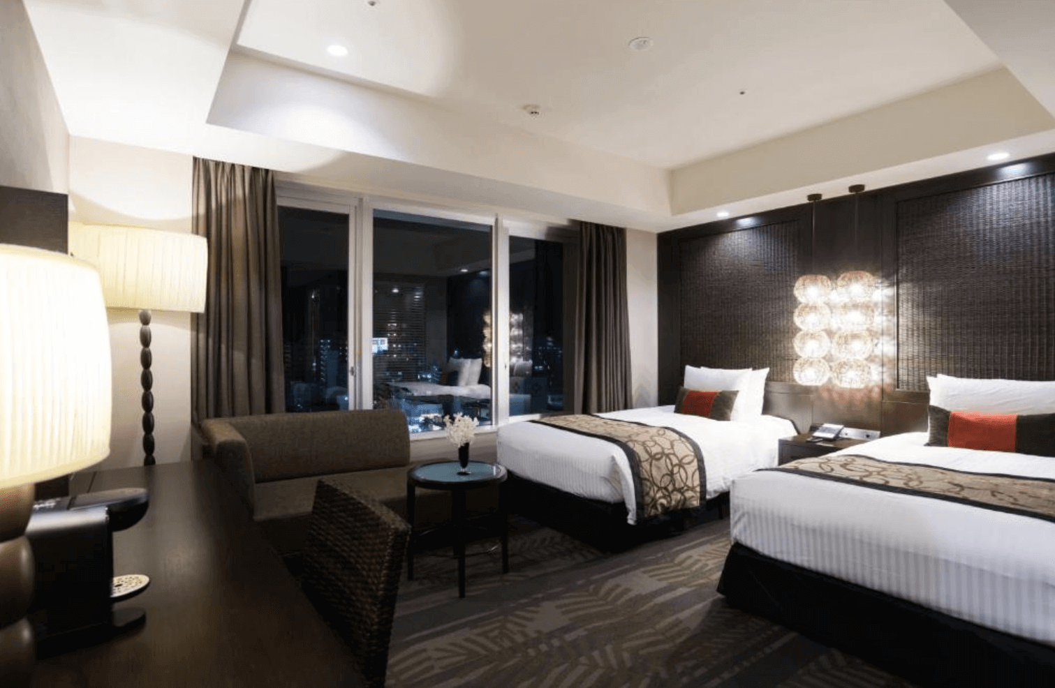 【那霸住宿】沖繩麗嘉皇家大飯店客房 — 兩張單人床搭配米色床單與木質家具，窗外可見市景與藍天。