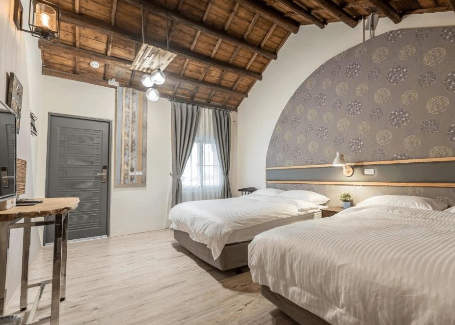 【太麻里住宿】海道民宿四人房，木質地板搭配木屋斜頂設計，兩張雙人床簡約舒適，牆面以花紋弧形裝飾增添質感。