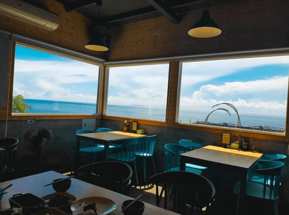 【太麻里住宿】海道民宿餐廳空間，大面積落地窗可欣賞遼闊海景，藍色椅子與木桌營造悠閒氛圍。