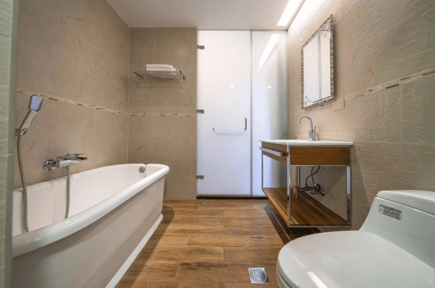 【吉安住宿】海邊很近民宿衛浴空間，設有獨立浴缸、木質地板、洗手台與馬桶，整體採暖色系牆面設計。