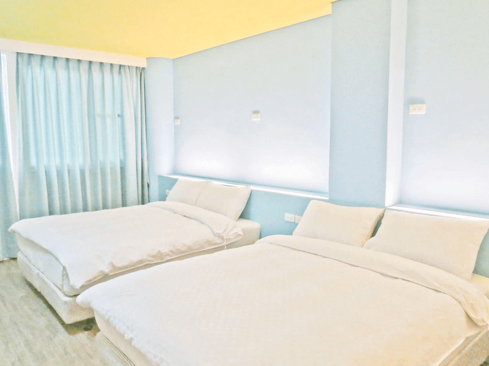 【太麻里住宿】狀元樓商務旅店四人房，兩張雙人床搭配淺藍色牆面與柔和燈光，空間明亮簡約。