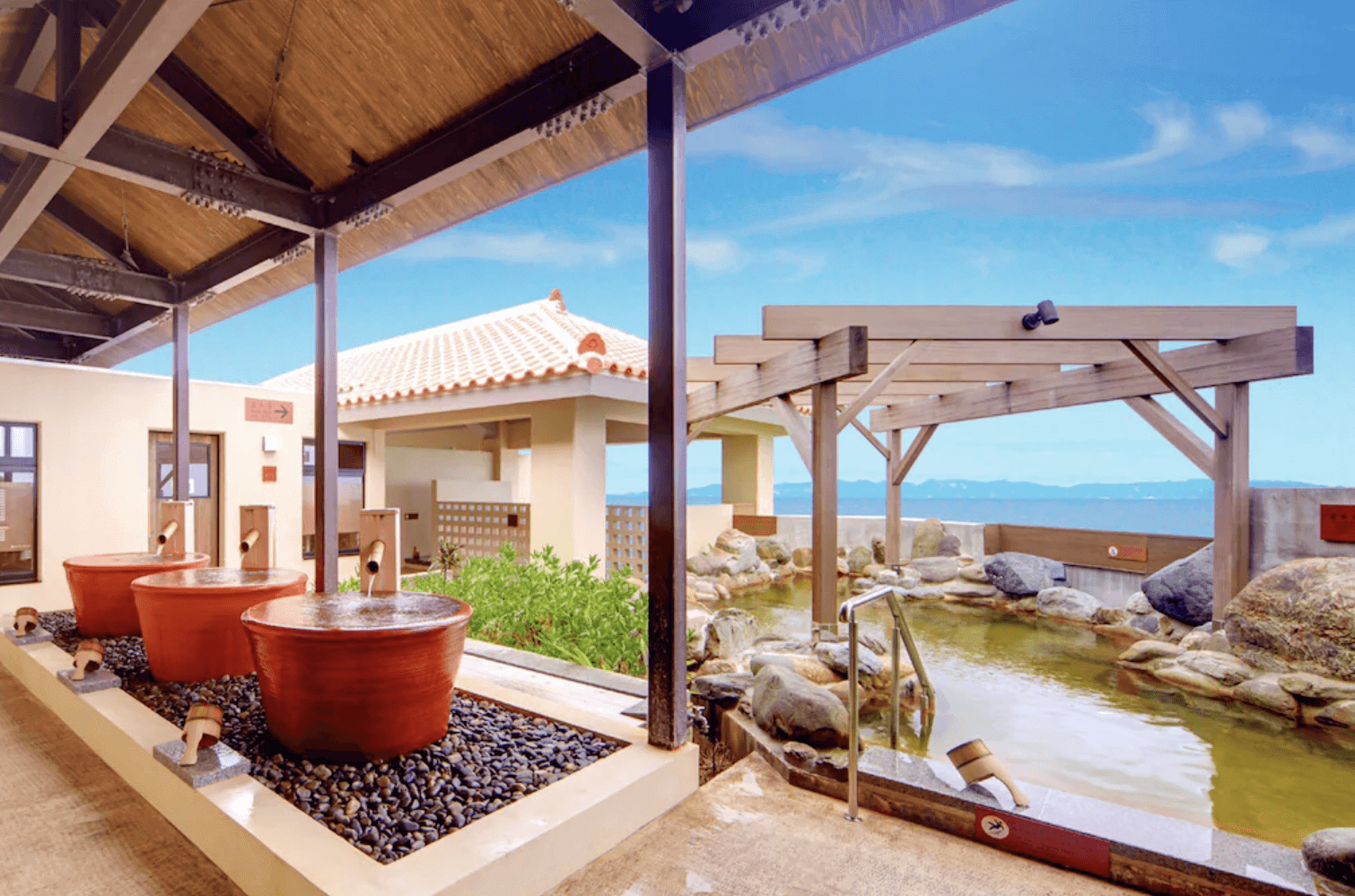 【那霸住宿】琉球溫泉瀨長島飯店露天溫泉 — 日式風格的戶外湯池，包含三個陶製圓形湯池與一座被岩石環繞的大型溫泉池，可眺望藍天與海景。