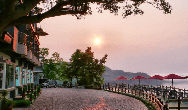 【太麻里住宿】環山雅築戶外景色，夕陽餘暉灑落在建築與山林間，紅色陽傘座位區營造浪漫氛圍。