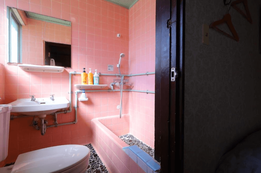 【名護住宿】白濱鄉村飯店 (Vintage Inn Shirahama Hotel) 浴室，粉紅色磁磚設計，配有浴缸、洗手台與淋浴設備，氛圍懷舊簡樸。