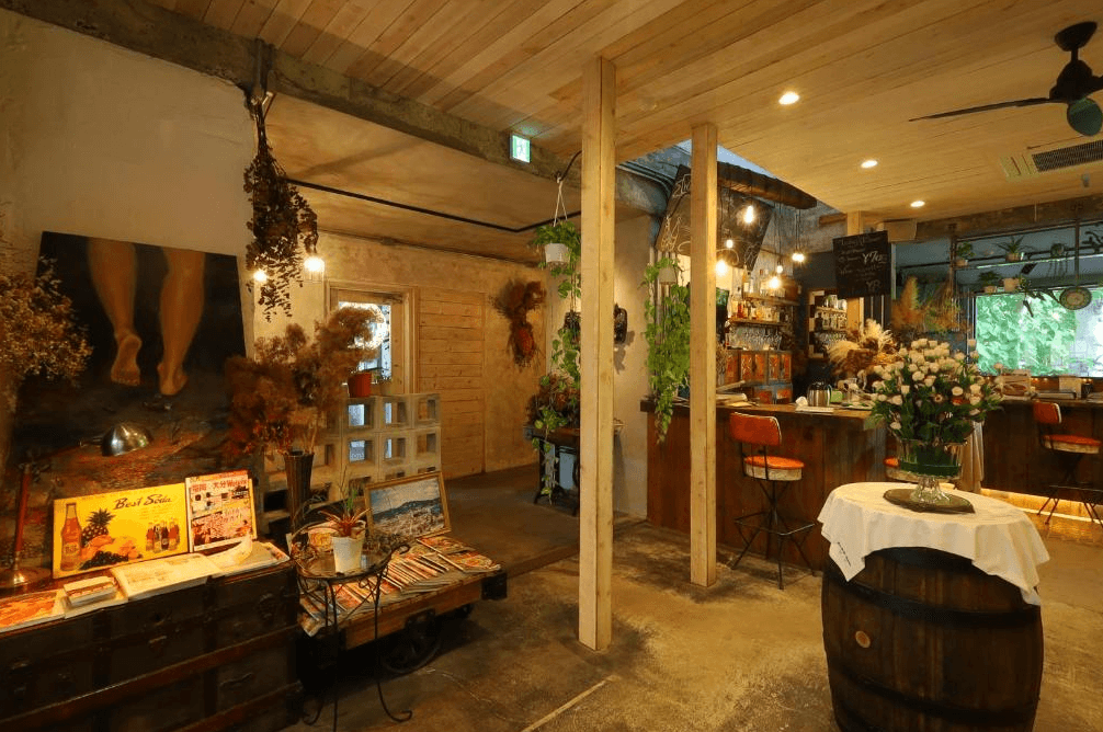 【名護住宿】白濱鄉村飯店 (Vintage Inn Shirahama Hotel) 大廳空間，結合咖啡吧與復古擺設，木質裝潢搭配乾燥花與藝術品，營造溫馨放鬆的氛圍。