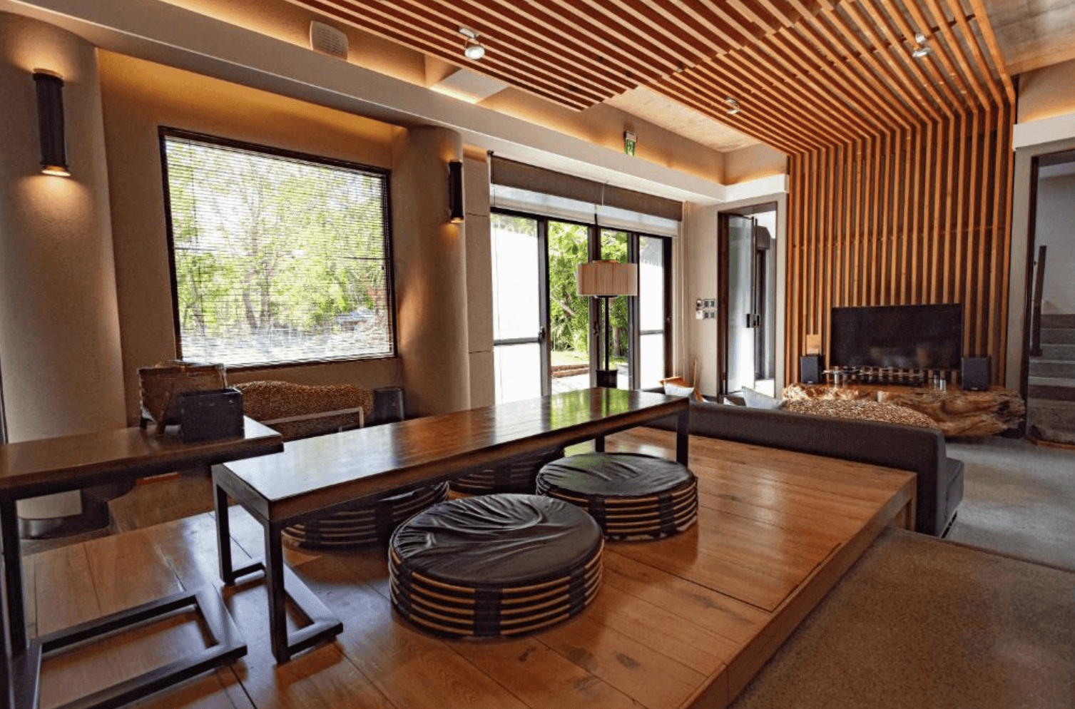 【恆春住宿】白砂15 villa 民宿交誼空間，原木地板與挑高格柵天花板設計，設有日式風格和式座位區與客廳電視牆，是旅人放鬆或小型聚會的絕佳空間。