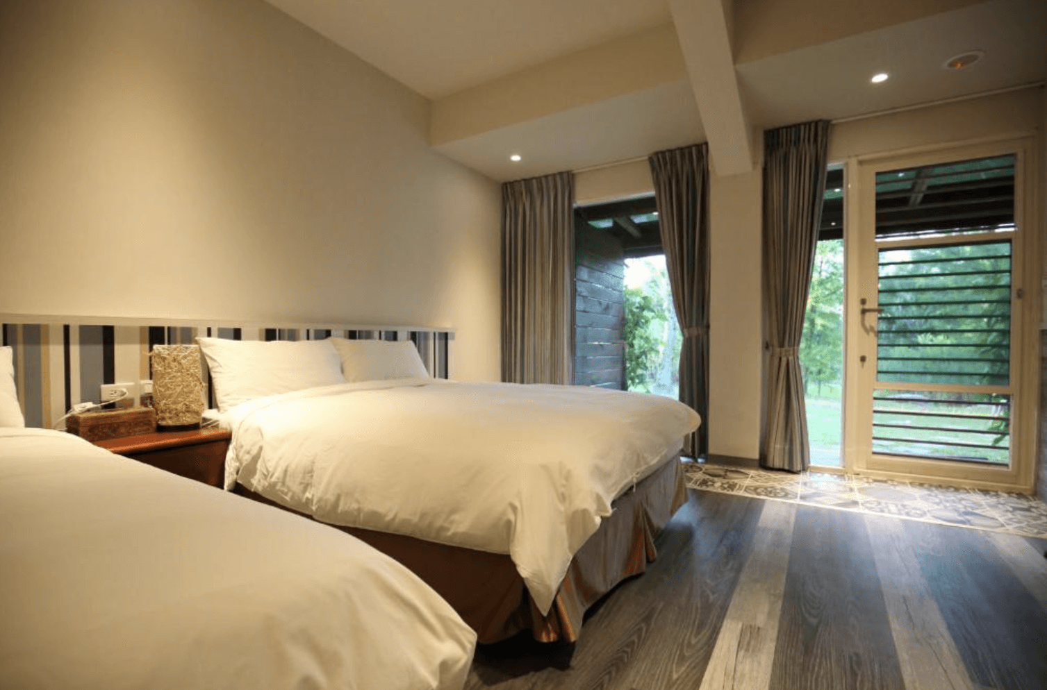 【吉安住宿】白陽山莊 雙床景觀房 — 簡約暖色系設計，配有兩張大床與落地窗，可直通戶外綠地，享受自然景色。