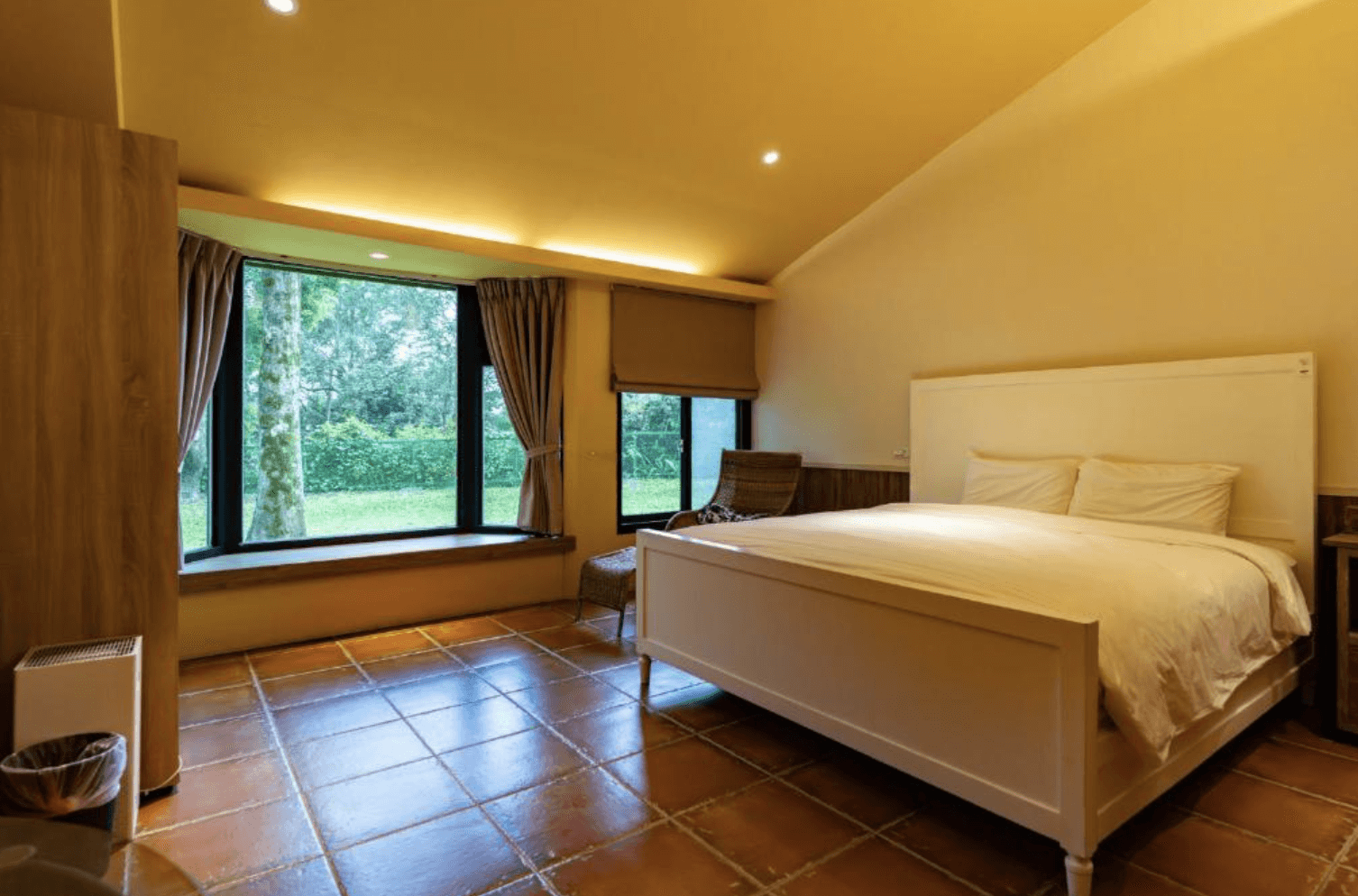 【吉安住宿】白陽山莊 景觀雙人房 — 溫暖燈光與木質地板設計，大面觀景窗外是綠意盎然的庭園景觀，營造舒適氛圍。
