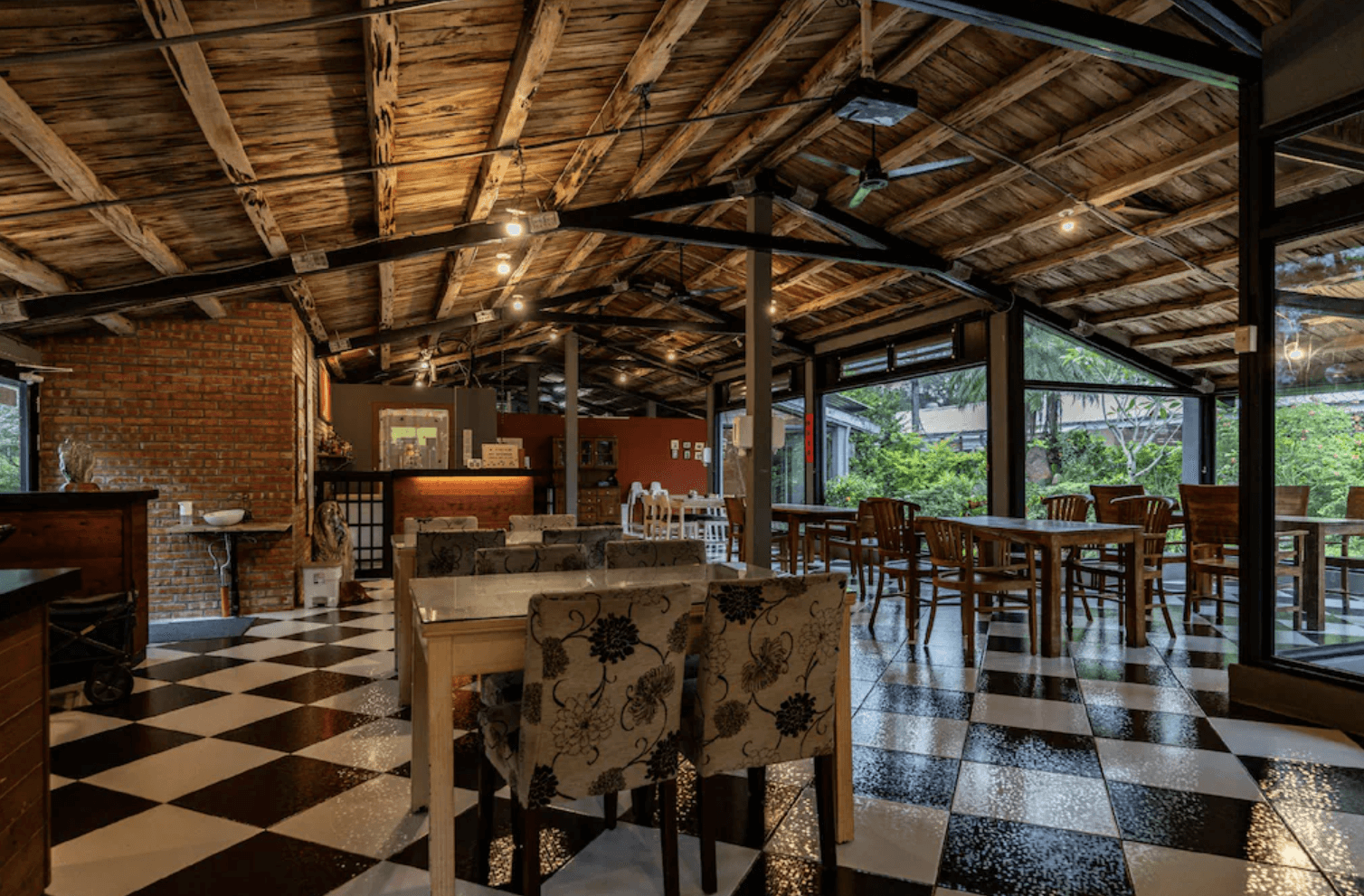 【吉安住宿】白陽山莊 餐廳空間 — 復古木質屋頂搭配黑白棋盤格地板，採用大量玻璃窗引入自然光，並設有多組用餐桌椅。
