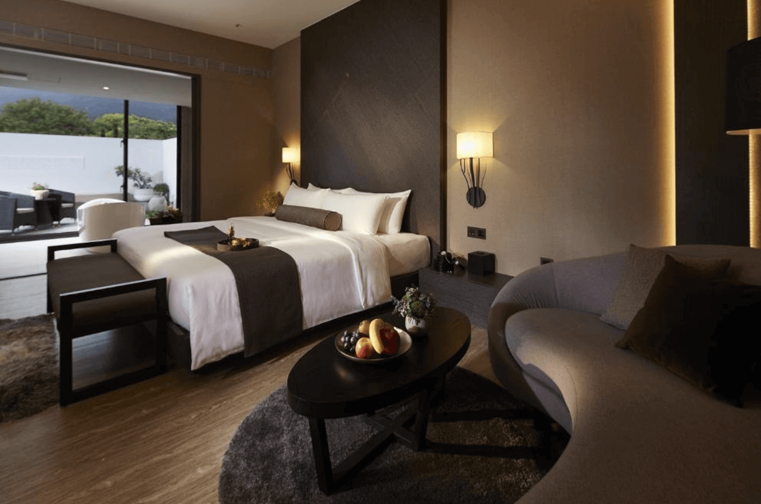 【吉安住宿】秧悦美地度假酒店 豪華客房 — 現代風格設計的大床房，溫暖色調搭配深色傢俱，設有戶外陽台與休憩區，窗外可見綠意景觀。