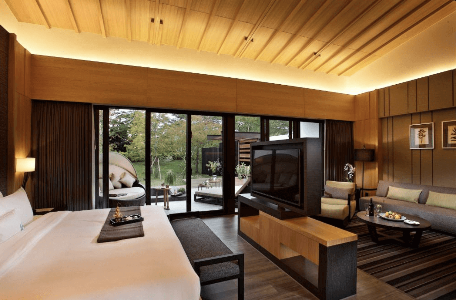 【吉安住宿】秧悦美地度假酒店 行政套房 — 木質天花與暖色系裝潢，配備大床、沙發區與大型液晶電視，房內可直通戶外花園與陽台座椅。