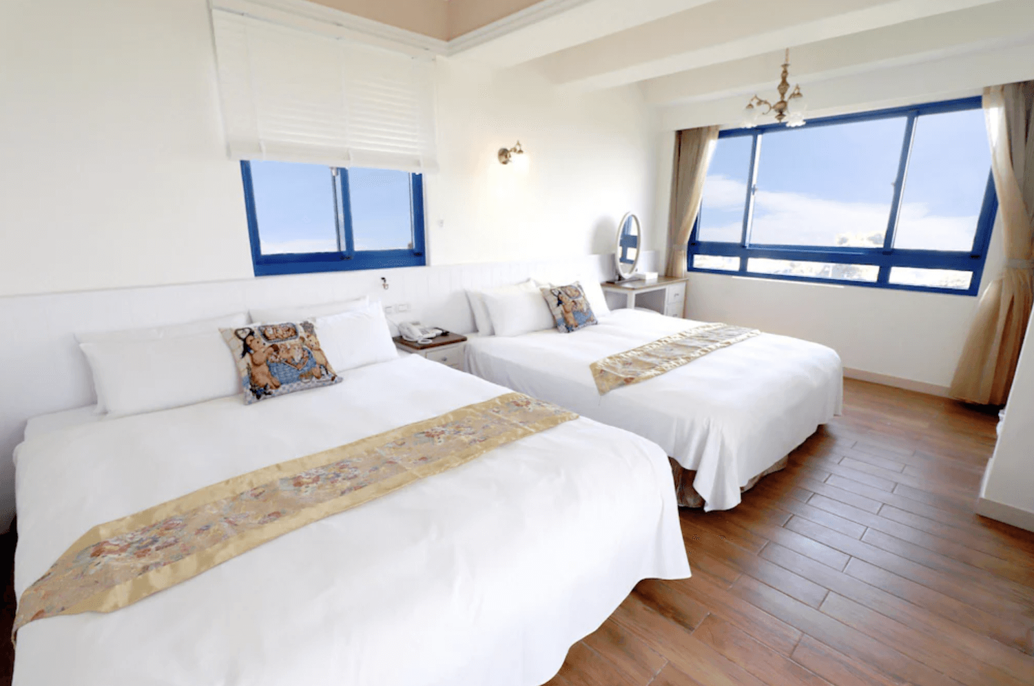 【吉安住宿】自在海民宿四人房室內景觀，木質地板、白色牆面與藍色窗框設計，採光明亮，房內設有梳妝台與床頭櫃。