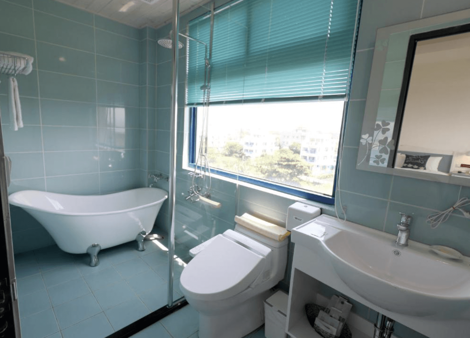 【吉安住宿】自在海民宿浴室空間，藍色磁磚牆面，配置獨立浴缸、淋浴間、馬桶與洗手台，窗外可見綠意景觀。