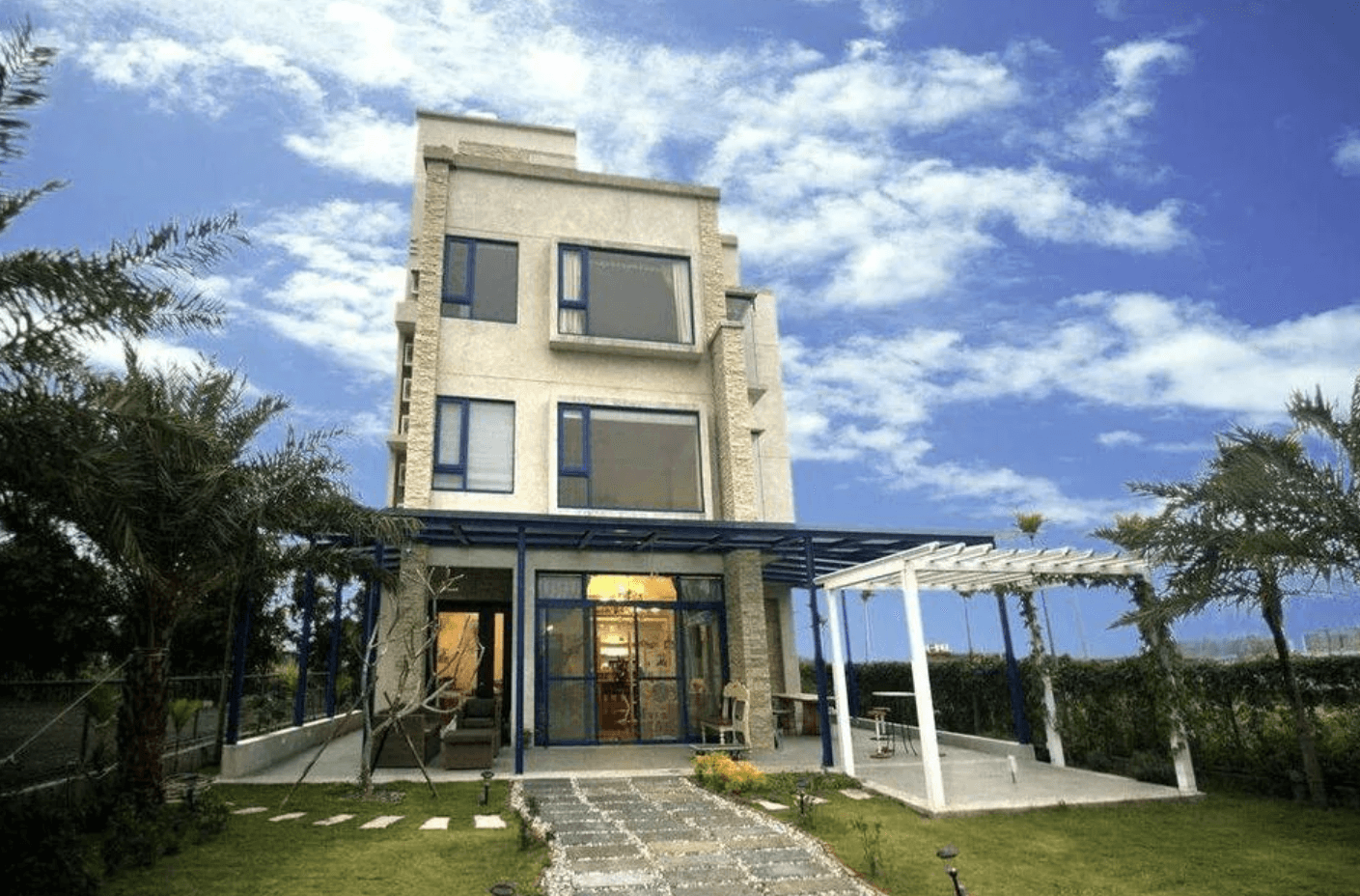 【吉安住宿】自在海民宿外觀全景，三層樓建築以淺色外牆與藍色窗框為特色，前方有草坪與白色花架，環境清新宜人。