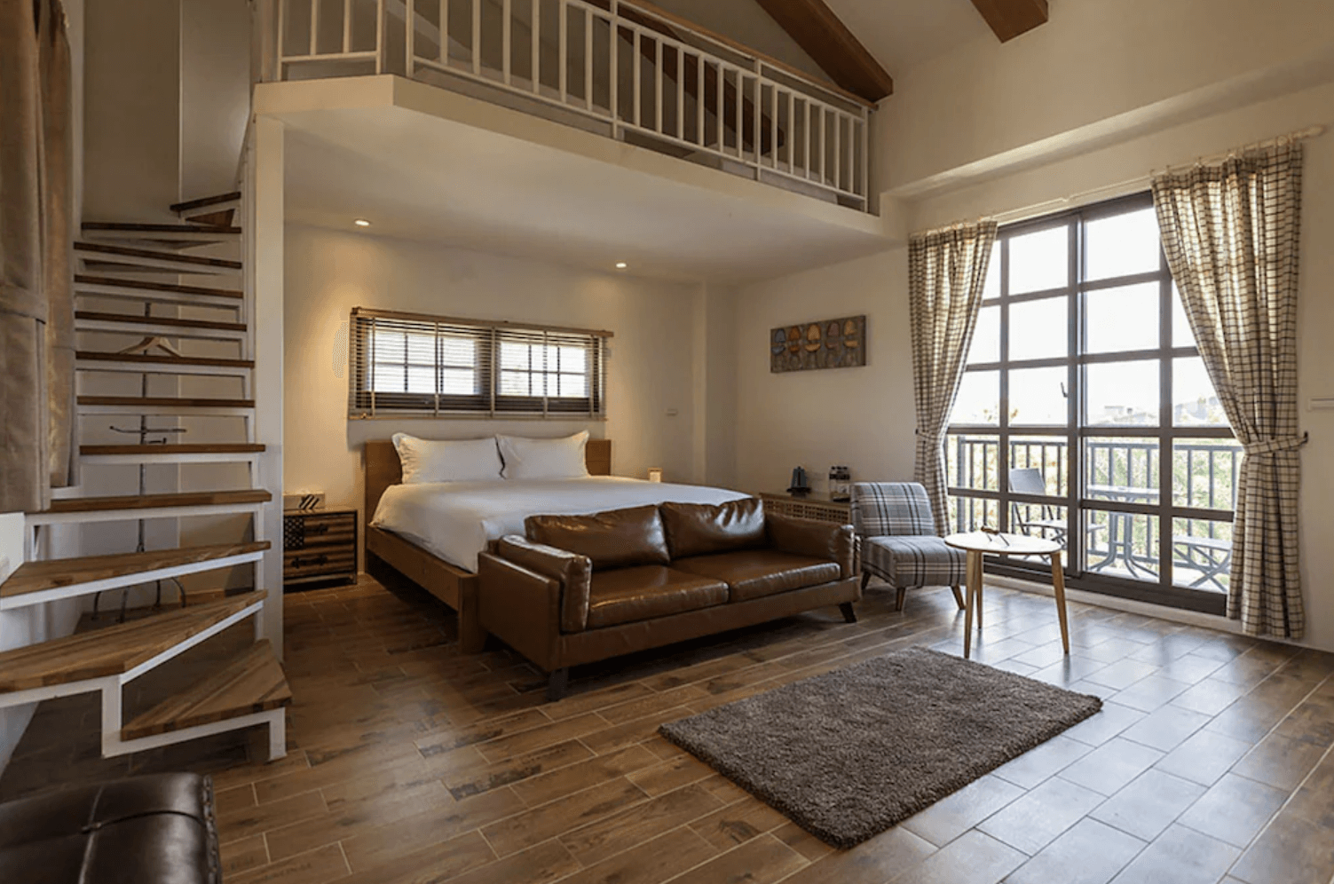 【吉安住宿】花蓮森林中民宿 閣樓雙人房 — 木質地板與溫暖色調設計，設有閣樓空間、大床、皮革沙發與落地窗，可欣賞戶外景致。