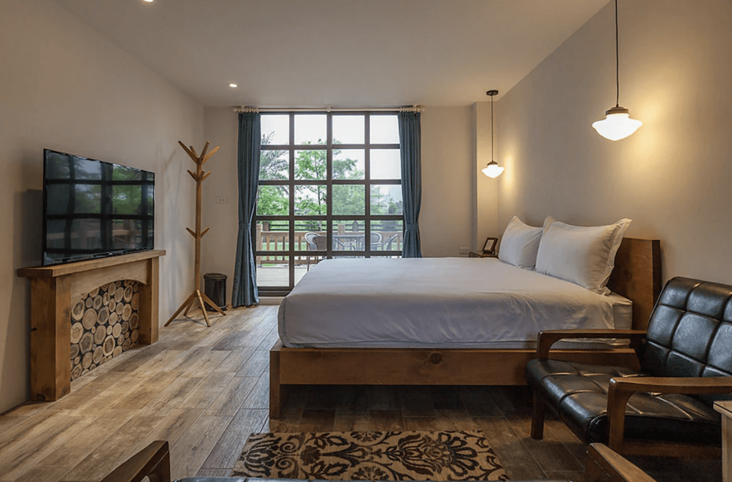 【吉安住宿】花蓮森林中民宿 景觀雙人房 — 大面落地窗引入自然光，房內設有大床、沙發椅與電視，並附有觀景陽台。