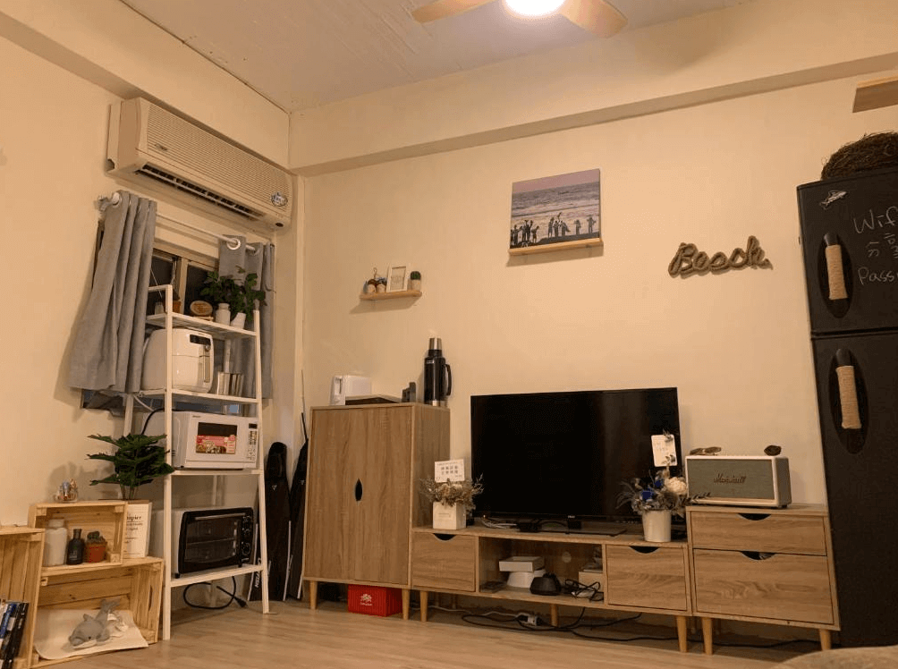 【蘭嶼住宿】那天 THat day Hostel 公共空間：客廳內有電視、木質收納櫃與裝飾，提供微波爐、烤箱等廚房電器，佈置溫馨方便旅人使用。