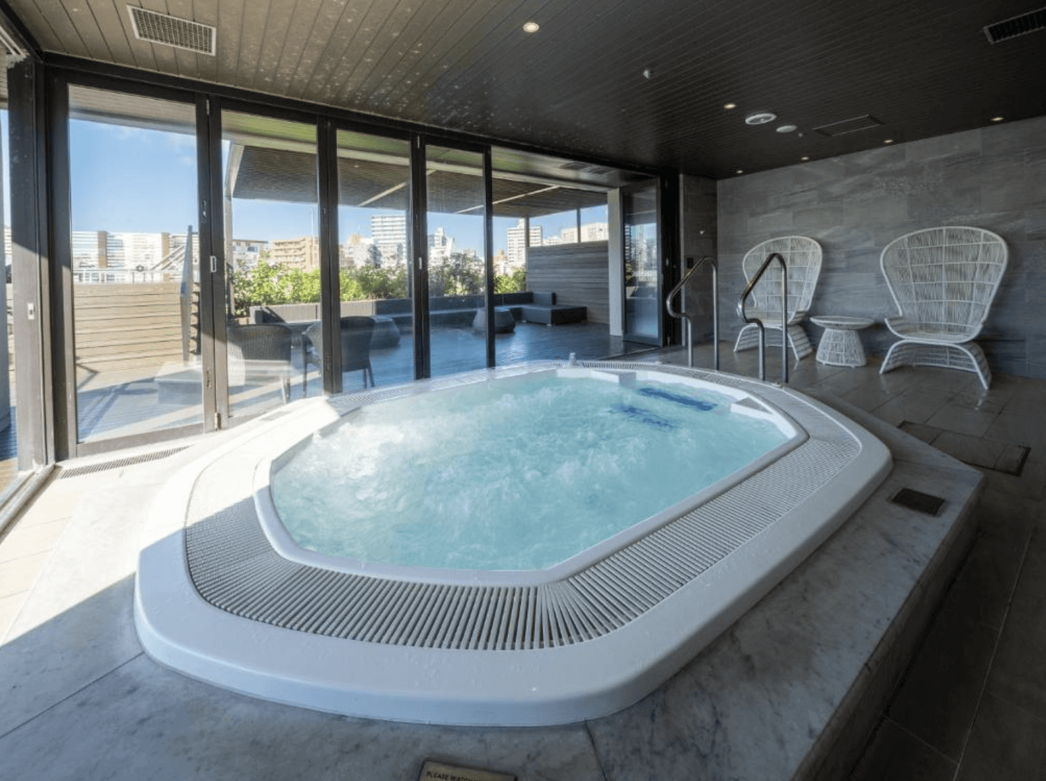 【那霸住宿】那霸凱悅酒店沖繩室內按摩池 — 室內溫水按摩池配備大片落地窗，連通室外露台，可享受放鬆泡湯與城市景致。