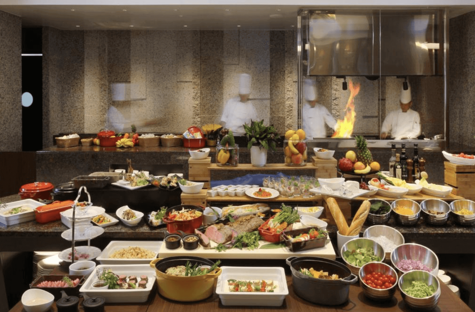 【那霸住宿】那霸凱悅酒店沖繩自助餐廳 — 各式豐盛的自助餐檯擺放新鮮沙拉、熟食、麵包、甜點與現場烹飪料理，廚師在後方現場烹調。