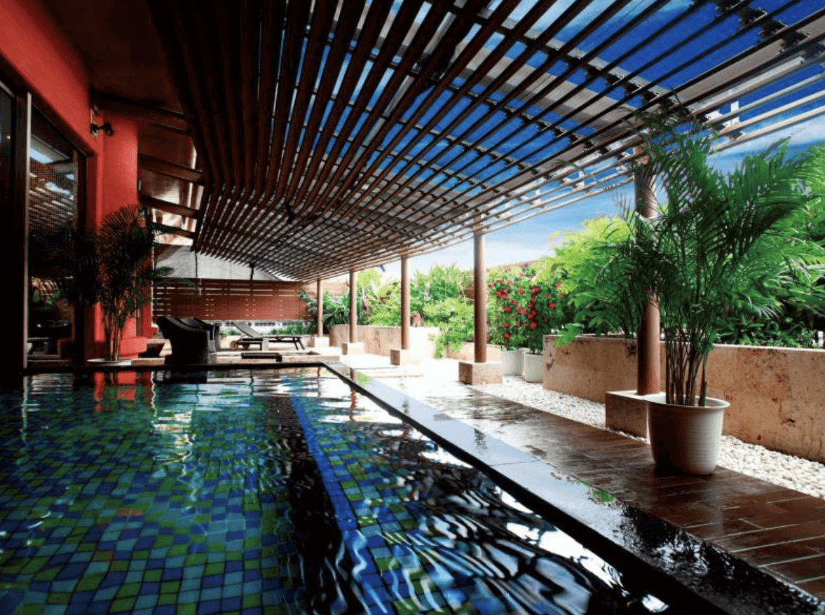 【那霸住宿】那霸遙索爾Spa中心酒店室內溫水泳池 — 馬賽克磁磚泳池區設有木質遮棚與綠植環繞，旁邊配置躺椅，營造放鬆舒適的環境。