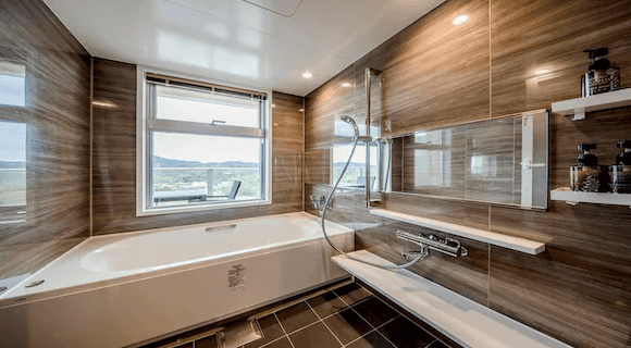 【名護住宿】里耶塔中山旅館 (Lieta Nakayama) 浴室，設有大型浴缸與淋浴設備，木紋牆面設計典雅，窗外可欣賞自然景觀。