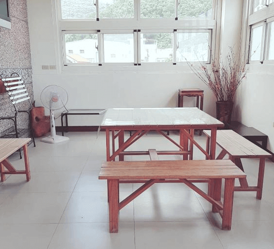 【金崙住宿】金崙鄉村民宿公共交誼空間，配置木製長桌與長椅，大片窗戶採光良好，可供房客休息或用餐。