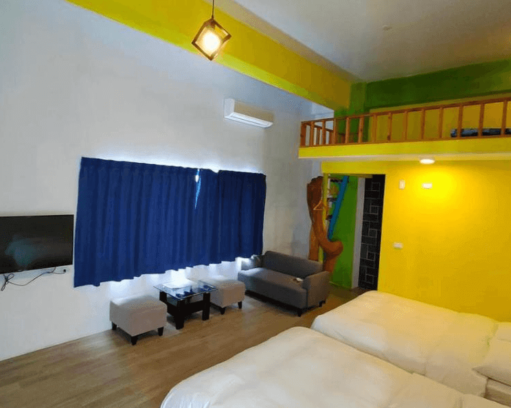 【金崙住宿】金崙雜貨店兒子民宿親子四人房，鮮明黃色與綠色牆面搭配閣樓空間，房內設有兩張大床、沙發與小茶几，空間寬敞明亮。