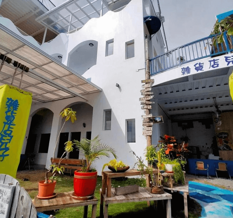 【金崙住宿】金崙雜貨店兒子民宿白色建築外觀，搭配藍色點綴與庭院綠植，整體風格明亮活潑，充滿海邊小鎮氛圍。