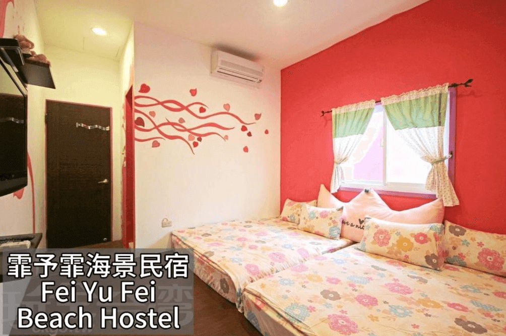 【蘭嶼住宿】霏予霏海景民宿客房二：房間以粉紅色與白色為主題，牆面有愛心裝飾，兩張雙人床搭配花卉圖案床單與粉嫩抱枕，呈現浪漫溫馨氛圍。