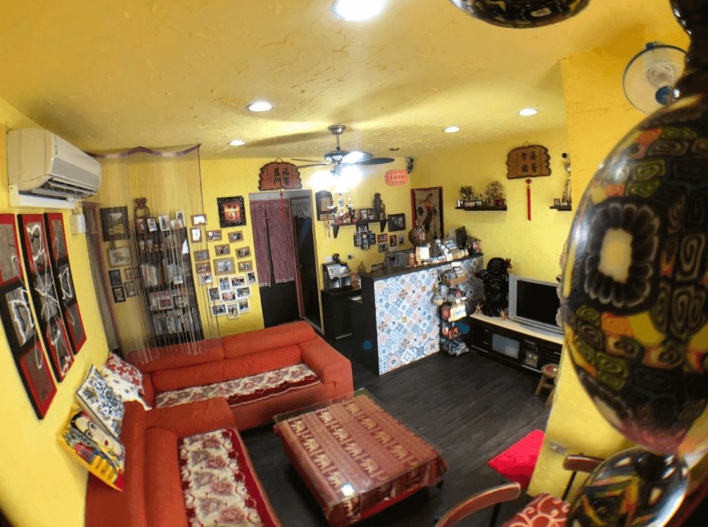 【蘭嶼住宿】霏予霏海景民宿大廳：黃色牆面搭配紅色沙發，牆上掛滿照片與裝飾，大廳一角設有電視與櫃台，整體充滿濃厚人情味與在地風格。