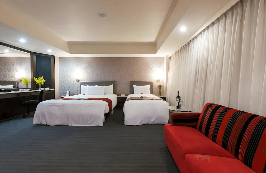 【板橋住宿】馥俐商旅 雙大床房，牆面以優雅壁紙裝飾，搭配紅色沙發與大片窗簾，適合家庭或多人入住。
