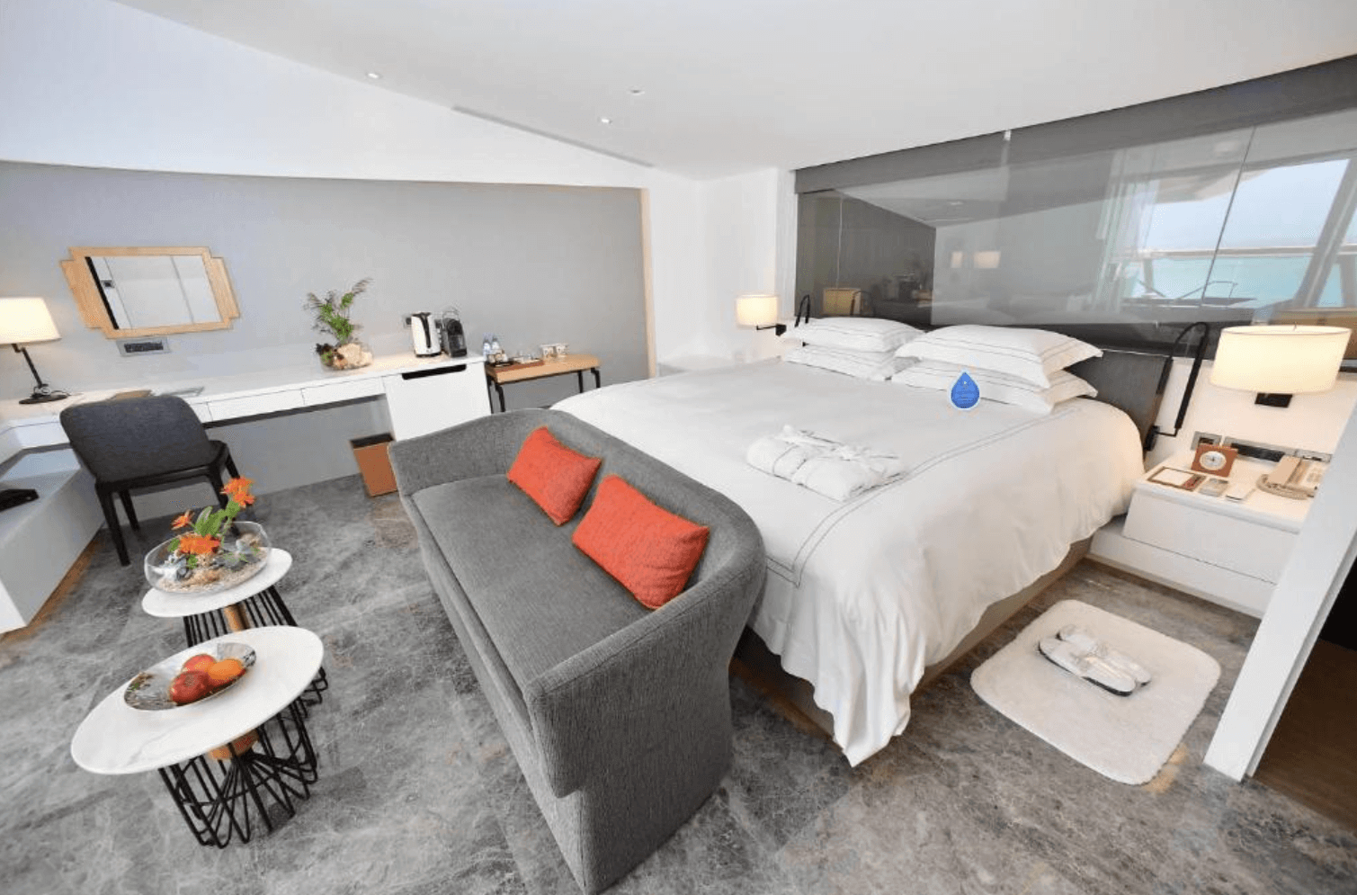 【恆春住宿】馥蘭朵墾丁 - 星沙灣海景房型，配有柔白雙人床、高質感沙發與簡約書桌，整體空間典雅舒適，設計融合現代與自然元素，窗外可見蔚藍海景。