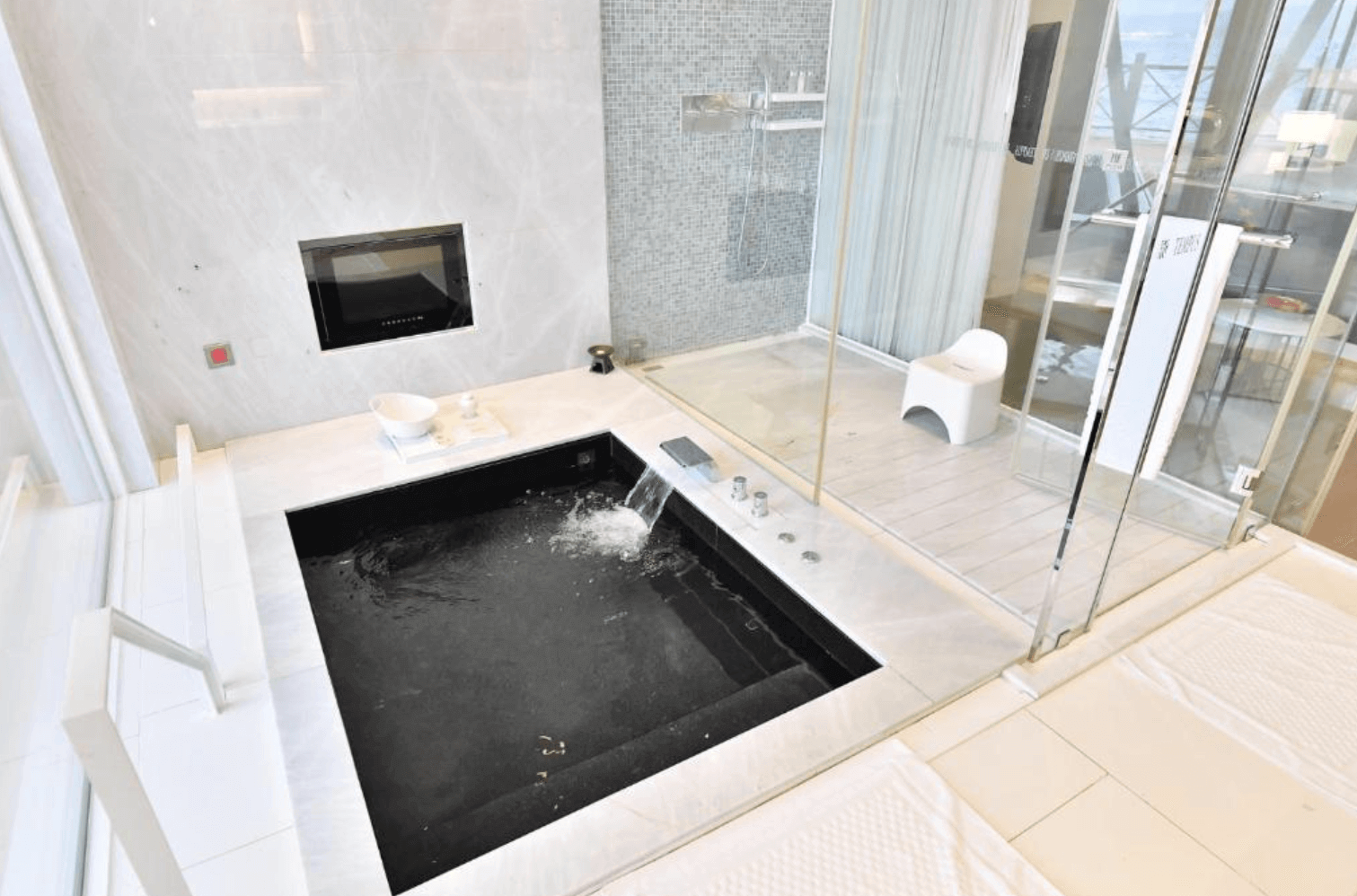 【恆春住宿】馥蘭朵墾丁 - 星沙灣客房內高級衛浴設施，擁有白色大理石地板、黑色按摩浴池與獨立淋浴間，空間寬敞明亮，帶來五星級的舒適體驗。