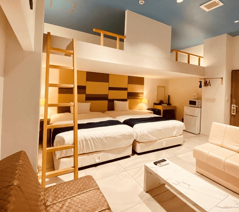 【名護住宿】鳳凰公園飯店 (Phoenix Park Hotel) 家庭房，兩張雙人床搭配溫暖燈光與簡約家具，設有樓中樓閣樓空間，並配有沙發、茶几、冰箱與微波爐，適合多人入住。