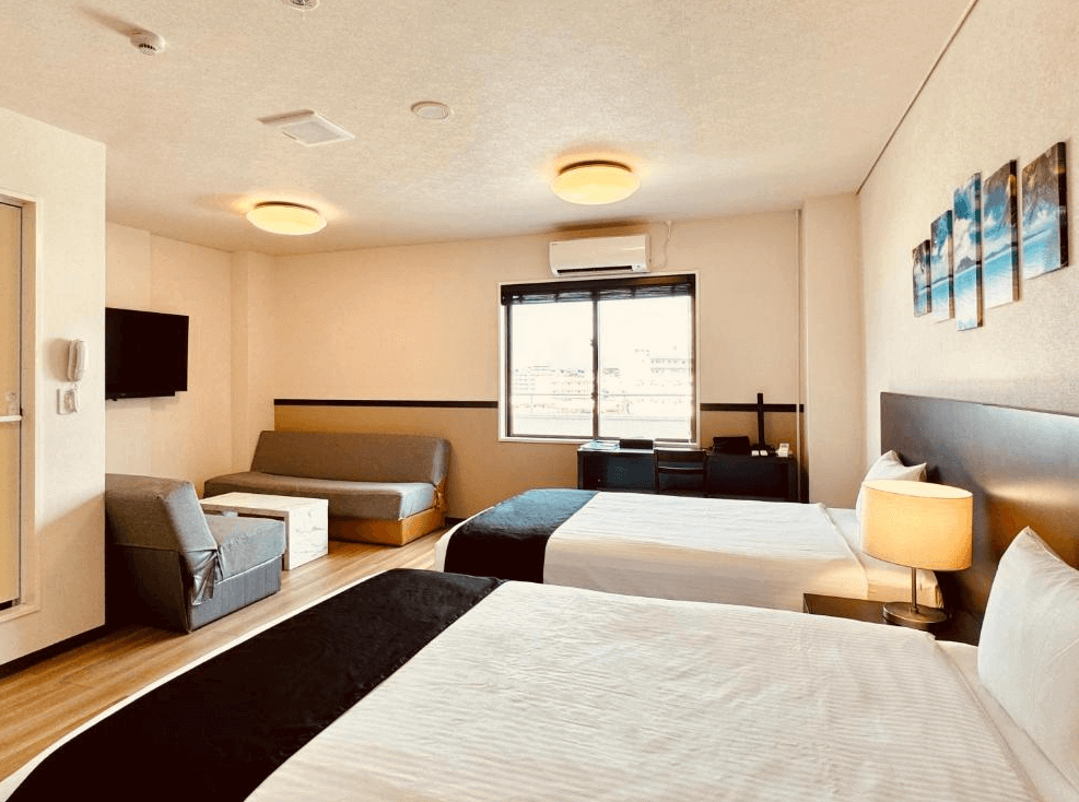 【名護住宿】鳳凰公園飯店 (Phoenix Park Hotel) 雙床客房，房內設有兩張大床、沙發、電視與辦公桌，採光明亮，可眺望窗外市景。