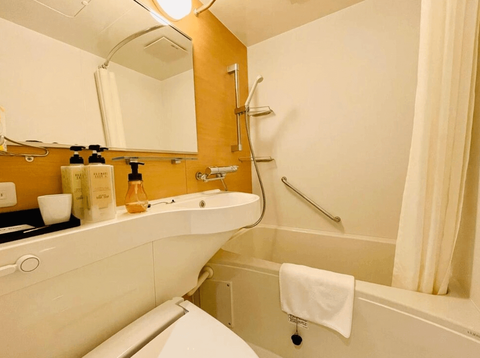 【名護住宿】鳳凰公園飯店 (Phoenix Park Hotel) 衛浴空間，乾淨明亮，配有免治馬桶、洗手台、大鏡面與浴缸，並提供洗沐用品與毛巾。