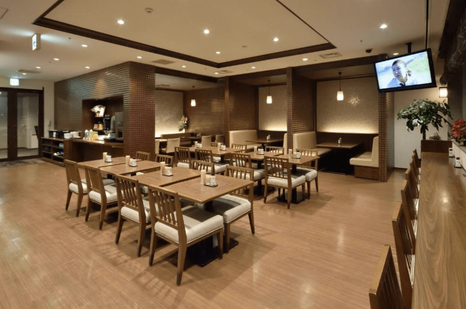 【小樽住宿】Dormy Inn小樽高級天然溫泉飯店餐廳，木質桌椅與柔和燈光布置，空間寬敞整潔，設有多人座位區與沙發座，提供住客舒適的用餐環境。