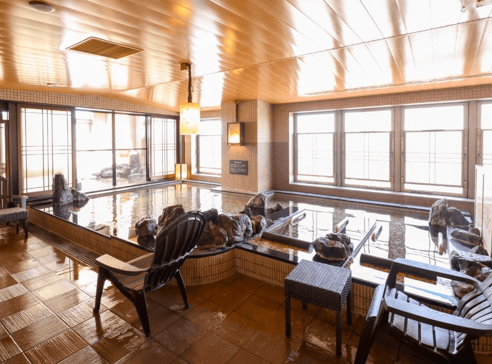 【旭川住宿】Dormy Inn飯店-旭川天然溫泉 (Dormy Inn Asahikawa Natural Hot Spring) 大浴場溫泉池，木質天花板搭配自然石造設計，提供舒適放鬆的泡湯環境。