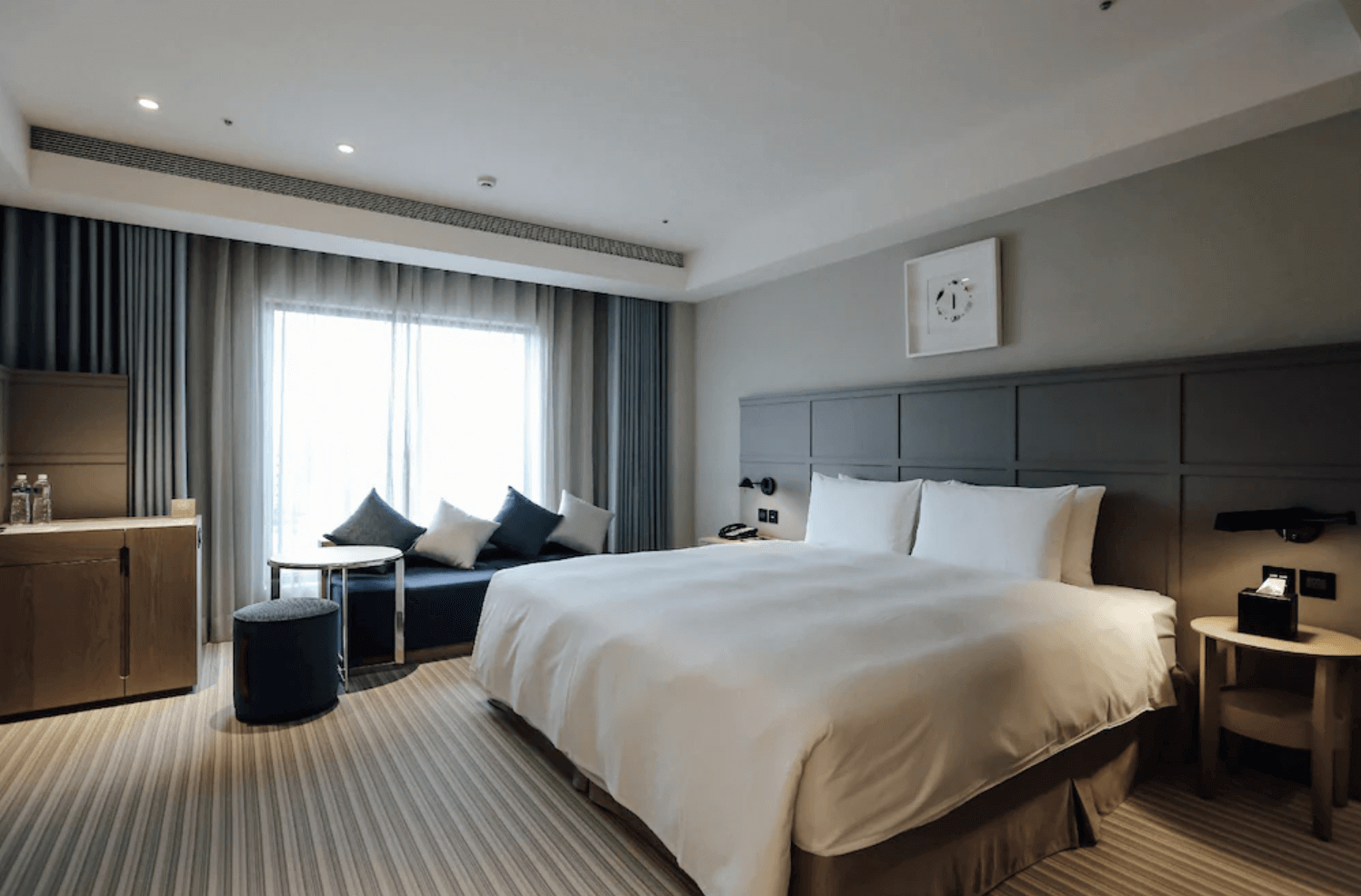 【前金住宿】Greet Inn 喜迎旅店 — 豪華客房：現代簡約風格的寬敞客房，配有大床、沙發與窗邊休憩空間，室內採光明亮。