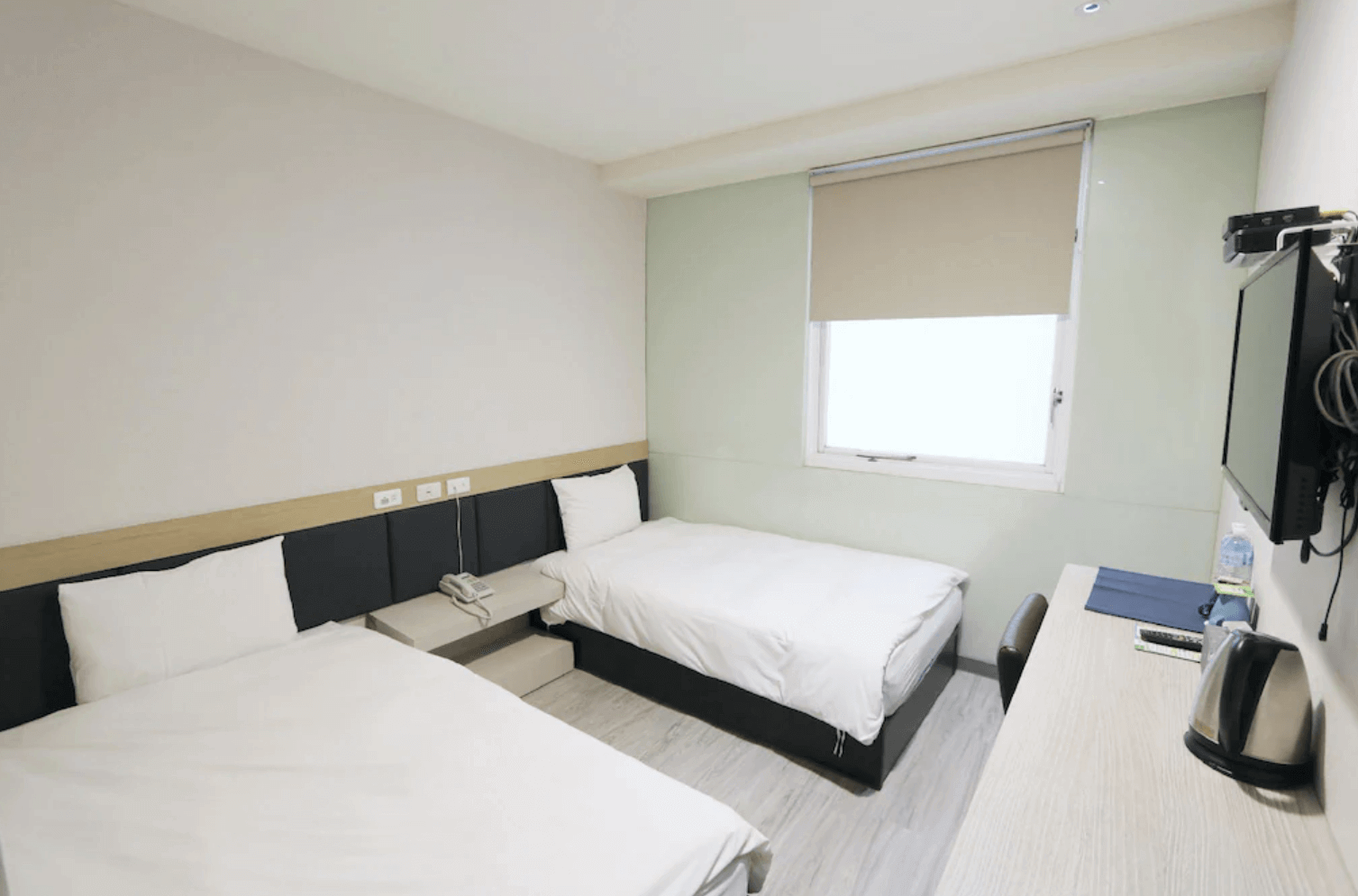 【前金住宿】兆舍行旅 雙床客房，簡約設計搭配木質地板，設有電視與書桌，空間清爽明亮。