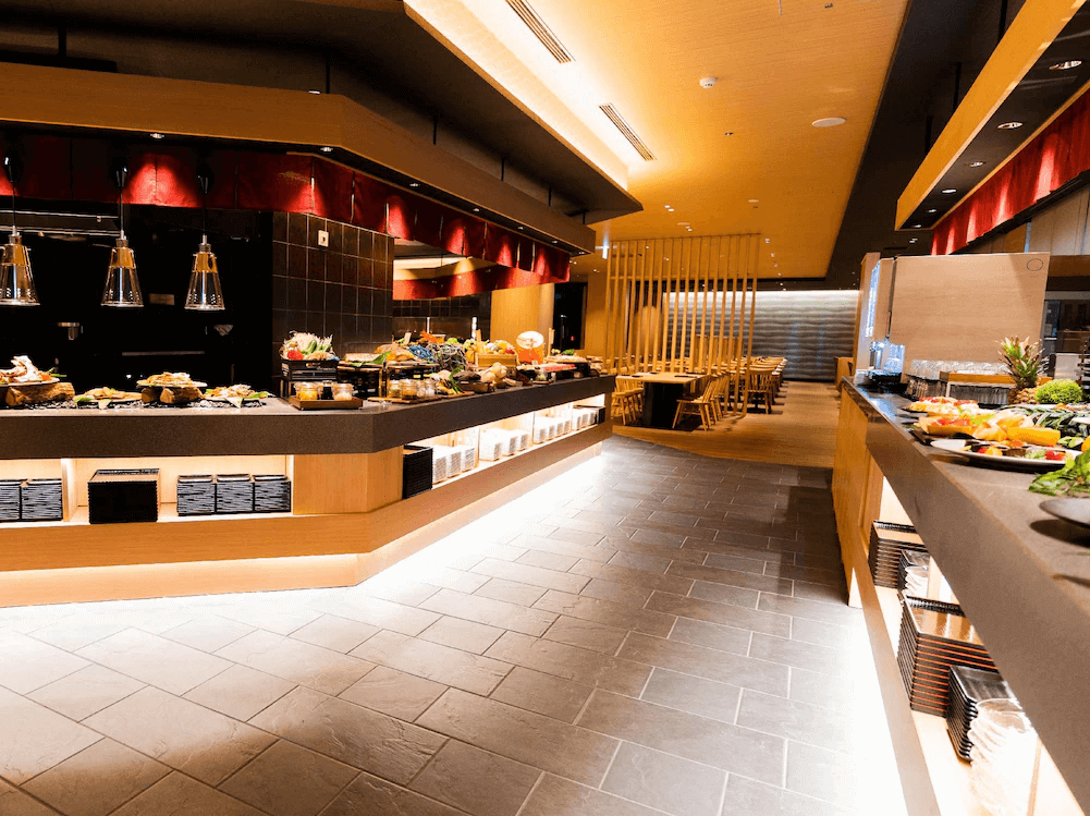 【函館住宿】函館湯之川溫泉海與燈休伊特度假村自助餐廳，現代日式風格設計，餐檯擺放多樣新鮮料理與水果，空間明亮舒適。