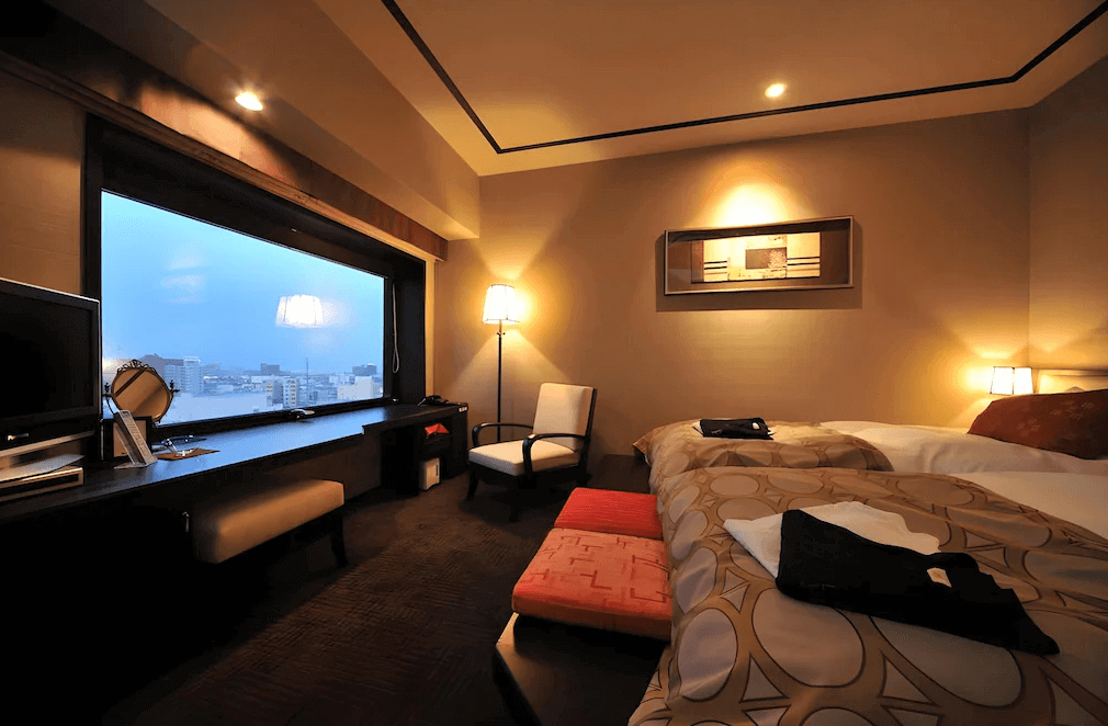 【函館住宿】函館灣 La Vista 飯店溫馨雙床客房，大片落地窗可眺望函館市景，室內以暖色系燈光與典雅裝飾營造舒適氛圍。